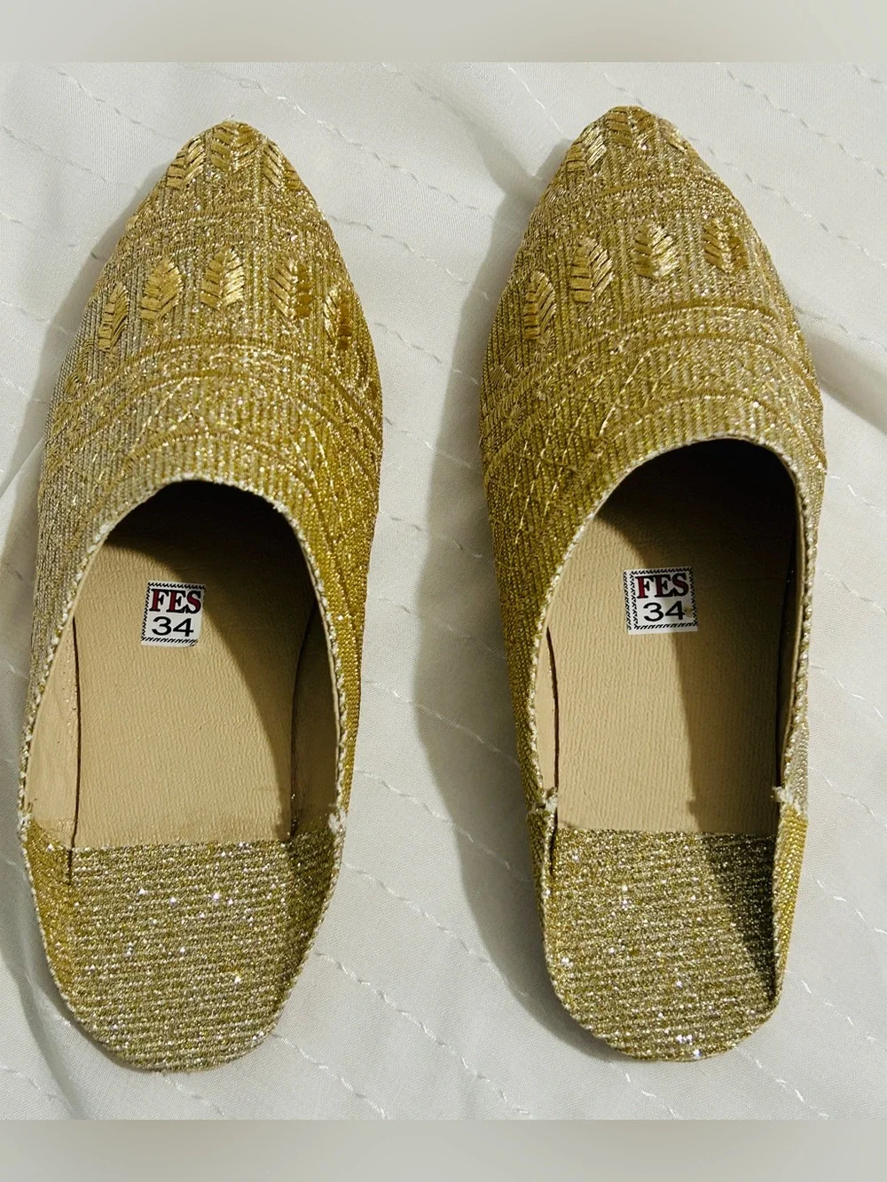 Moroccan babouche slippers adorned with intricate embroidery and a pointed toe.